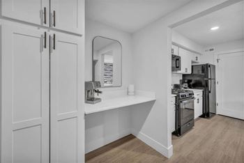 A kitchen with white cabinets and a wooden floor.